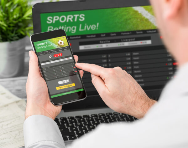 betting bet sport phone gamble laptop over shoulder soccer live home website concept - stock image